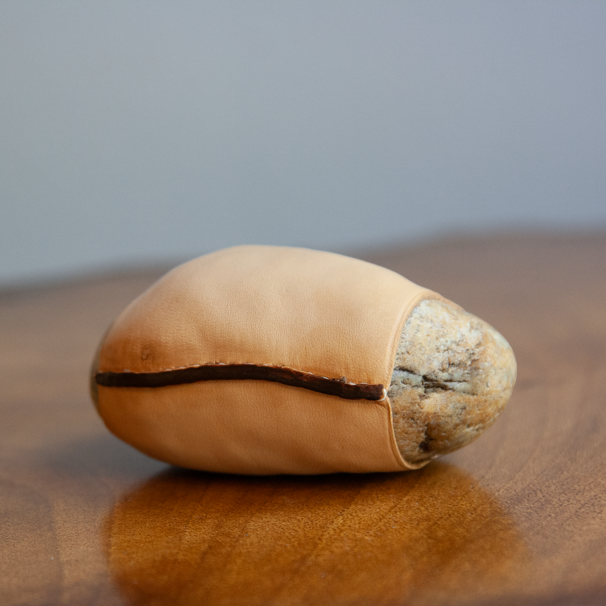 A modernist Austrian paperweight by Werkstätte Carl Auböck, crafted from a smooth Danube stone wrapped in supple leather. This Vienna-made design reflects Auböck’s signature blend of natural materials and refined craftsmanship.