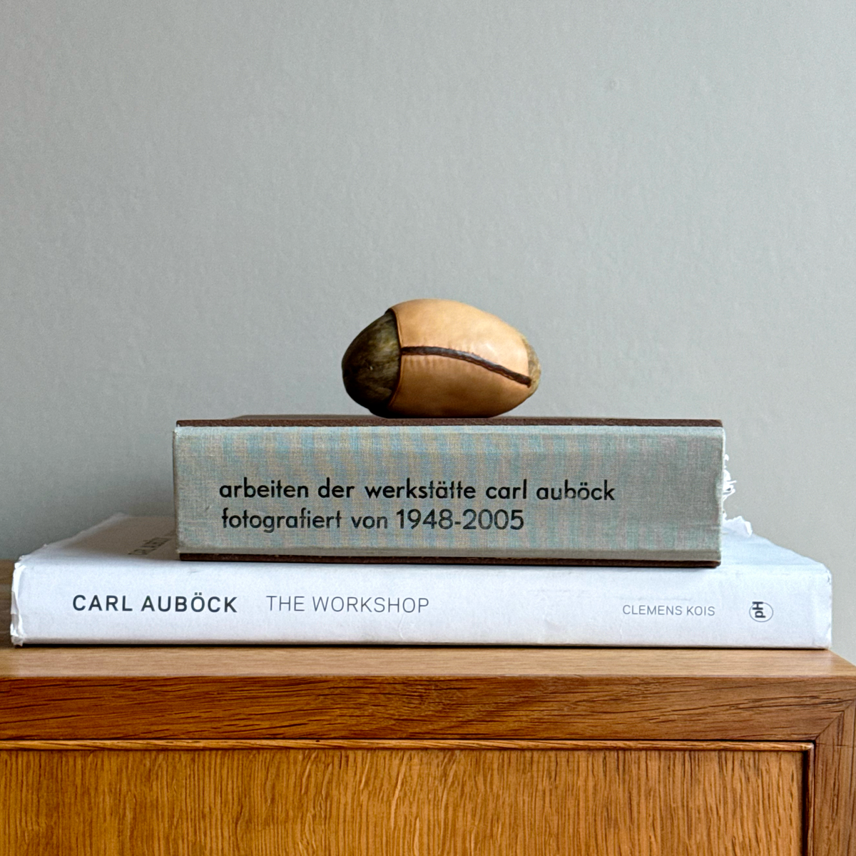 A handcrafted Austrian paperweight by Werkstätte Carl Auböck, featuring a smooth stone encased in rich leather. This sculptural mid-century design blends natural materials with refined craftsmanship, embodying Auböck’s distinctive modernist aesthetic.