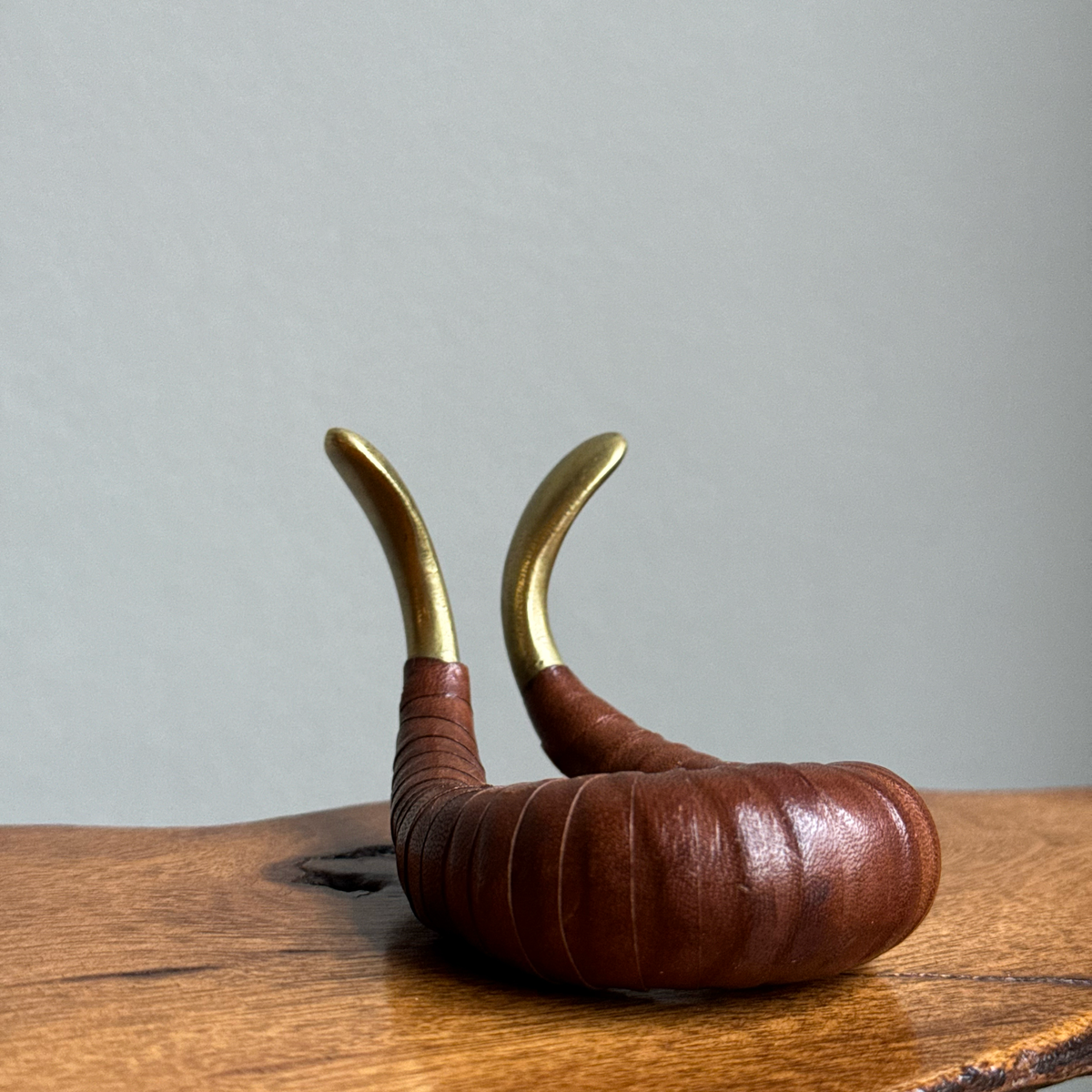 A vintage 1950s pipe holder or watch stand by Carl Auböck II, crafted from brass and leather. This versatile piece exemplifies mid-century modern design and the craftsmanship of the Auböck workshop.