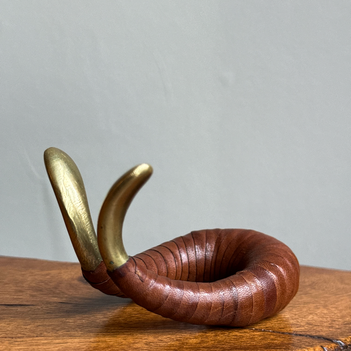 A vintage 1950s pipe holder or watch stand by Carl Auböck II, crafted from brass and leather. This versatile piece exemplifies mid-century modern design and the craftsmanship of the Auböck workshop.