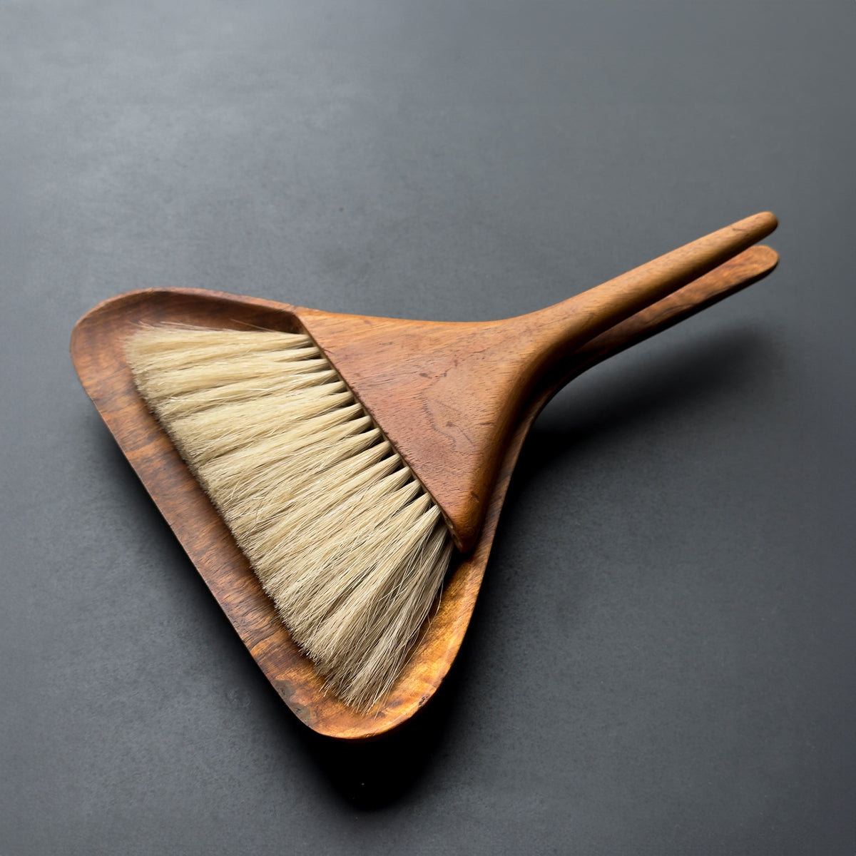 A table brush designed by Carl Auböck in the 1950s, featuring a walnut handle and horsehair bristles. This Austrian piece combines ergonomic, modernist design with elevated elegance, characteristic of mid-century craftsmanship.