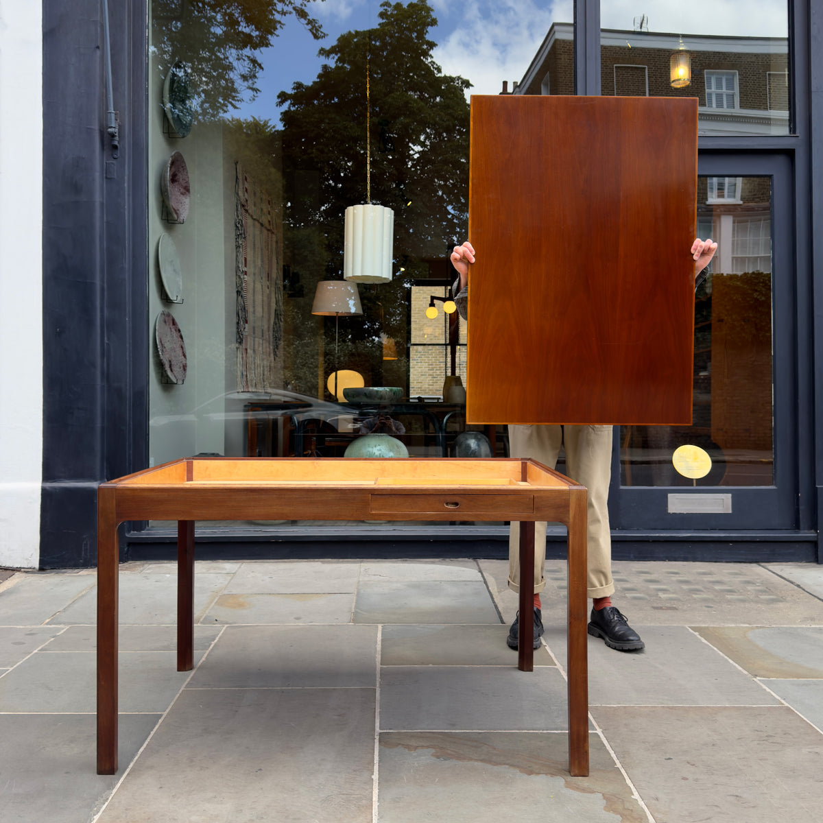 A 1950s Danish drafting table made of mahogany, featuring a reversible top, a drawer, and a central compartment. This piece combines functionality with classic mid-century design.