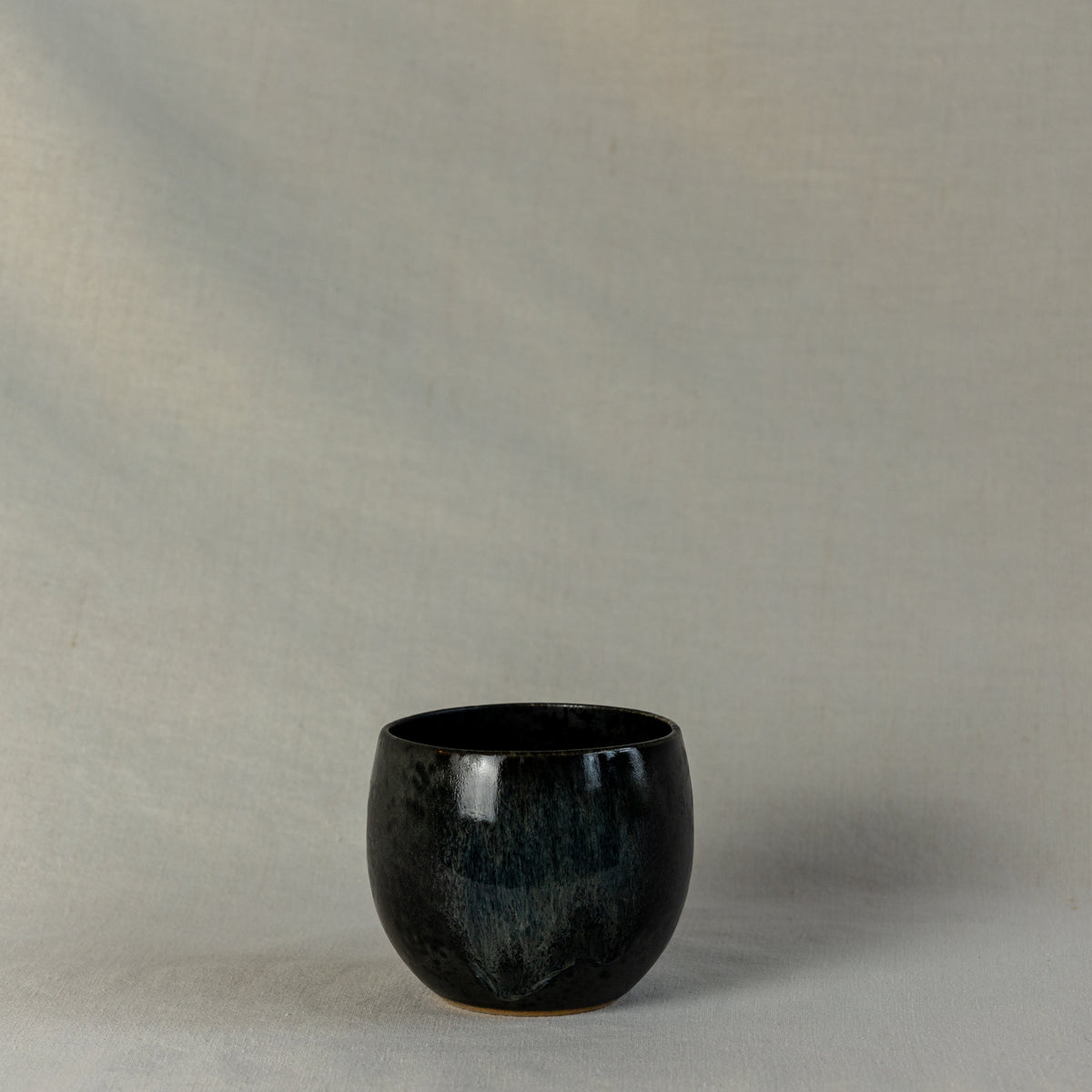 A handcrafted ceramic cup by Kasper Würtz, a Danish ceramicist renowned for his hand-thrown and hand-glazed stoneware. Inspired by Nordic utilitarian crafts and British studio pottery, the design features a balanced inner-outer ratio, subtle concavity, and a glaze that harmoniously blends matte and glossy finishes. Diameter: 7.5 cm, Height: 7.5 cm.