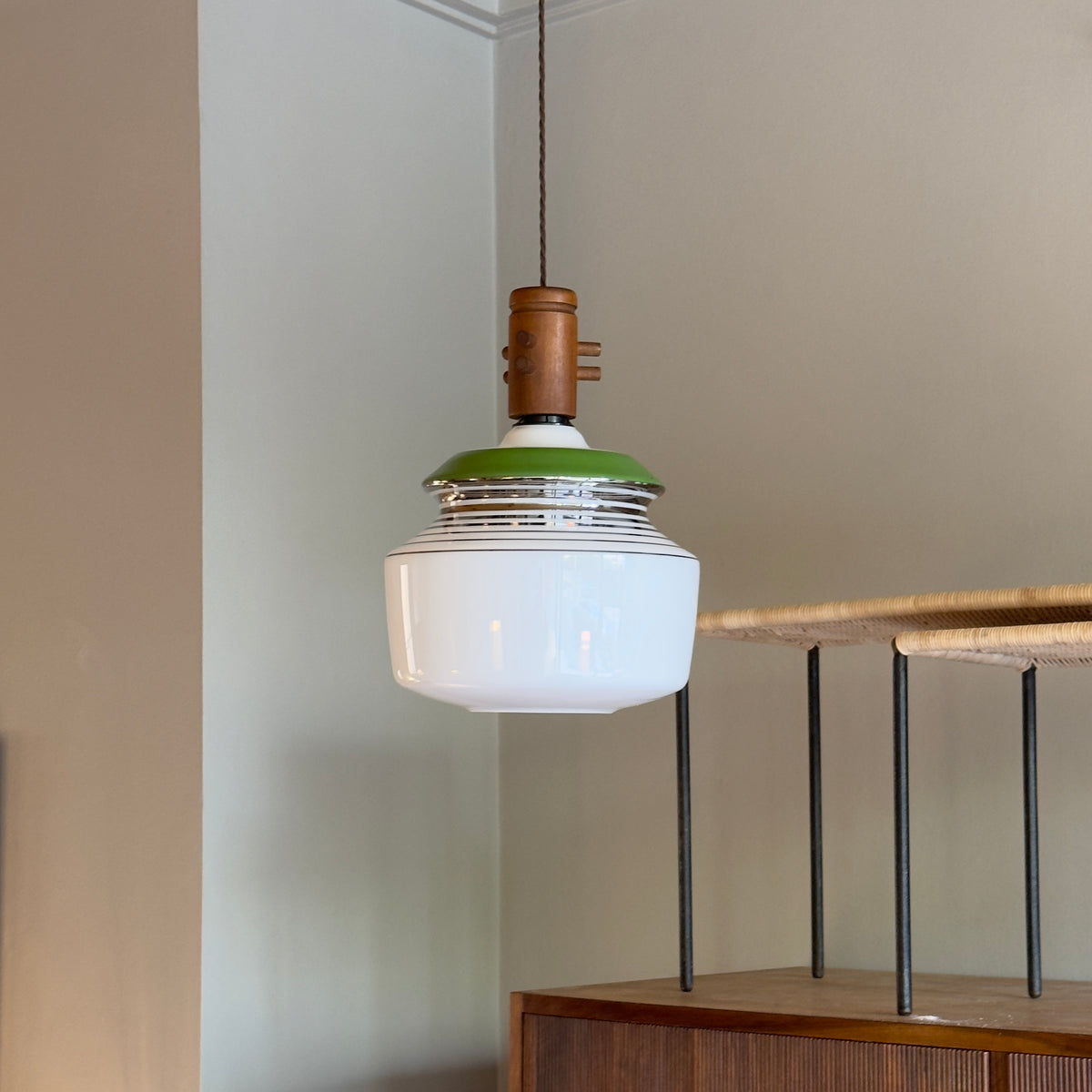 An opal glass pendant light with chrome accents, a green detail, and a wooden ceiling rose, produced by Slovakian manufacturer LIPTA. The design reflects the space-age aesthetics of the 1960s.