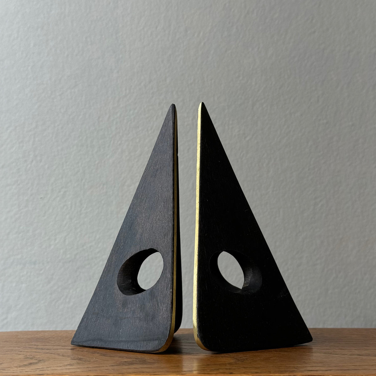 A solid cast brass bookend named 'Mask,' model 4100, designed by Carl Auböck. Based on a 1950s design, this piece is a sleek home accessory emblematic of modernist design.