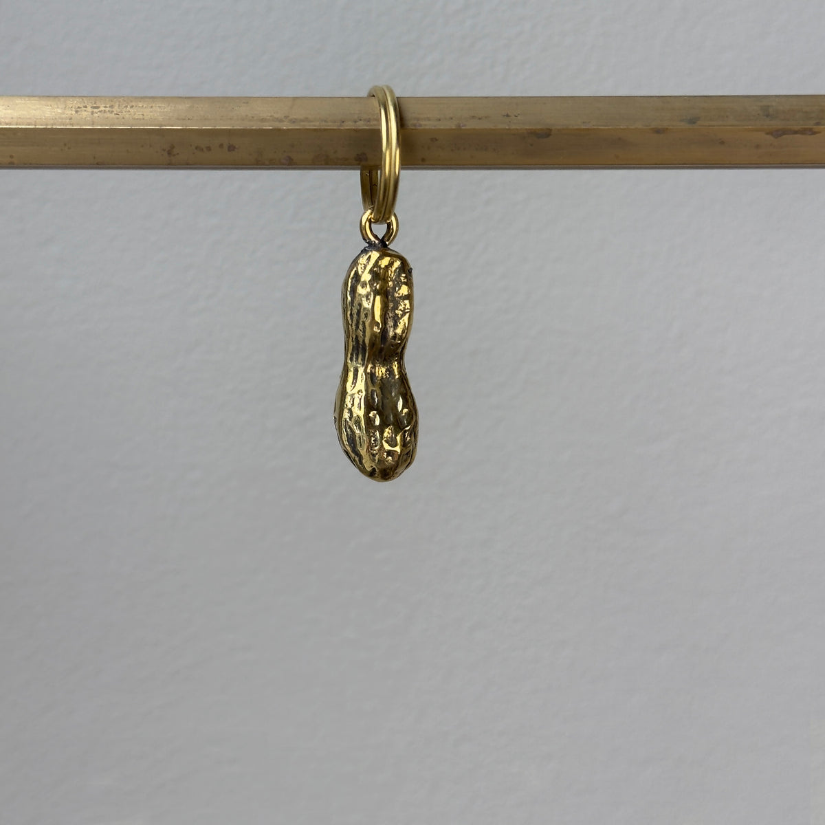 A playful peanut-shaped brass keyring designed by Carl Auböck, made in Vienna. This piece reflects modernist design with a whimsical touch