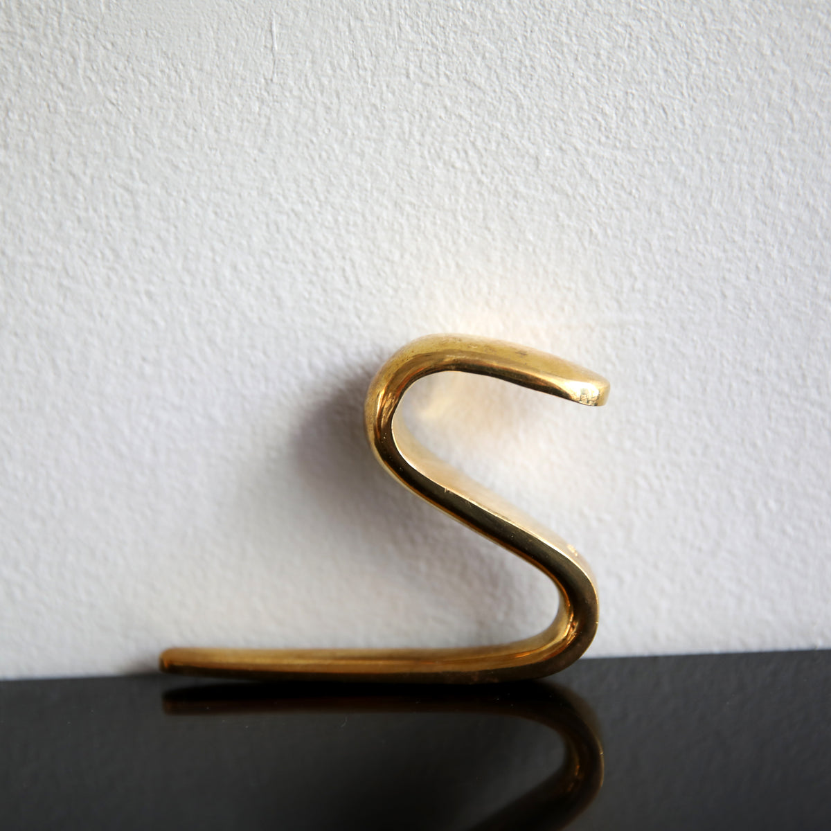 An S-hook designed by Carl Auböck, crafted in the Werkstätte Auböck workshop, Vienna, Austria. Made from brass and designed to be wardrobe-mounted, this piece reflects mid-century Austrian design and craftsmanship.