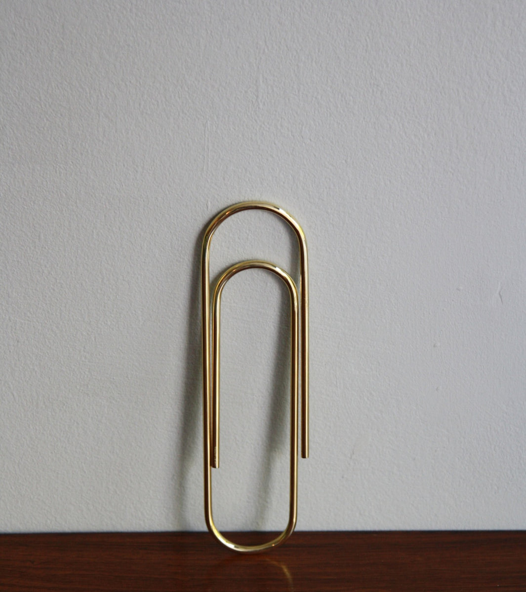 An oversized paper clip designed by Carl Auböck, crafted in brass and available at Sigmar London. This iconic midcentury design piece showcases the playful yet functional style of the Auböck workshop.