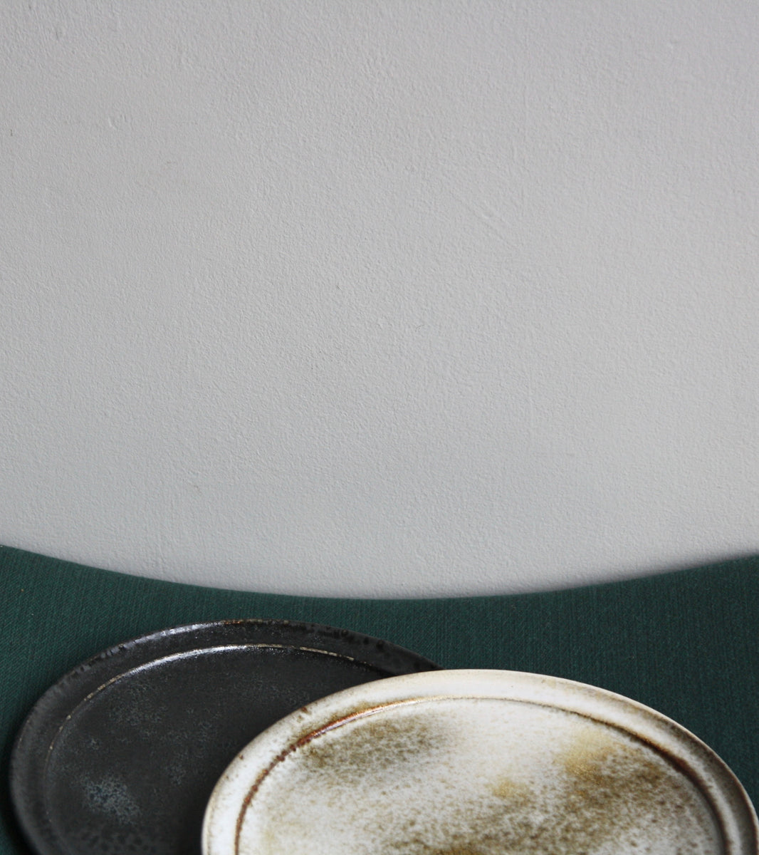 A handcrafted ceramic plate by Aage and Kasper Würtz, Danish studio ceramicists known for their distinctive hand-thrown and hand-glazed stoneware. Inspired by Nordic utilitarian crafts and British studio pottery, the design features a balanced inner-outer ratio, subtle concavity, and a harmonious interplay of matte and glossy glaze. Diameter: 27 cm, Height: 2 cm.